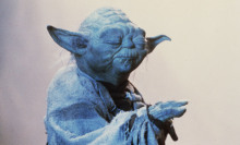 Yoda, a character from Star Wars with long pointed ears and a cloak, closes his eyes in meditation and holds a hand outstretched.