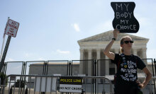 A pro-abortion rights protester stands in front of the Supreme Court holding a sign that reads, "My body, my choice."