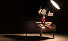 mickey mouse standing on piano in spotlight