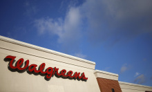 A Walgreens sign on the exterior of a building against a bright blue sky.