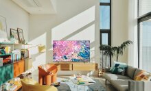 Samsung TV with colorful water screensaver on TV stand in sunlit room