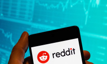CHINA - 2023/02/15: In this photo illustration, the American social news aggregation, web content rating and discussion website, Reddit logo is seen displayed on a smartphone with an economic stock exchange index graph in the background.