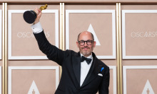 Director Edward Berger, wearing black and white formal wear accented with a blue ribbon, holds his Oscar at the 95th Academy Awards
