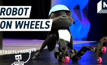 Disney's robot prototype sitting on stage wearing a pair of roller skates.