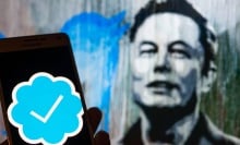 elon musk by screen with blue check