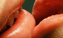 A close up of two people's lips touching. 
