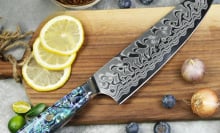 cutting board with slices of lemons and the master chef knife placed on top 