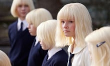 A group of children with the same blonde haircut stand in a line. 