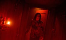 A young man walks into an entirely red lit room. 