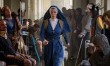 A nun in blue strides with purpose through a hospital.