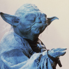 Yoda, a character from Star Wars with long pointed ears and a cloak, closes his eyes in meditation and holds a hand outstretched.
