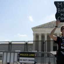 A pro-abortion rights protester stands in front of the Supreme Court holding a sign that reads, "My body, my choice."