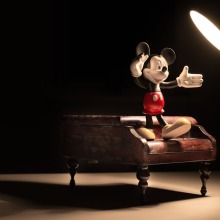 mickey mouse standing on piano in spotlight