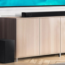 A soundbar is lying on top of a shelf, with a subwoofer towards its left.