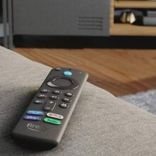 A Fire TV remote is lying on a couch.