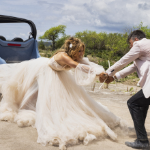Jennifer Lopez in a voluminous wedding dress that's stuck to an empty golf buggy, while Josh Duhamel holds her hands urgently.