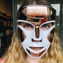woman wearing gold and white LED face mask