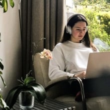 woman sitting in living room on her laptop wearing silver bose 700 headphones