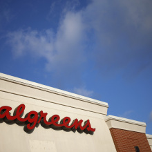 A Walgreens sign on the exterior of a building against a bright blue sky.