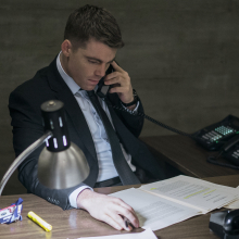 An FBI agent sits at a desk at night attending paperwork.