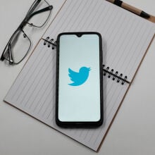 Twitter logo on phone screen on top of notebook