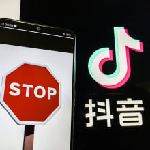 A stop sign on a phone screen and the TikTok logo with some Chinese characters