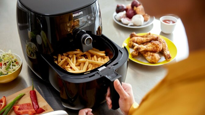 person cooking french fries in an air fryer
