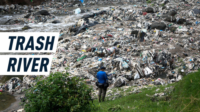 A man stands in front of a river which resembles a mountain of plastic more than a body of water. Caption reads: "Trash River"