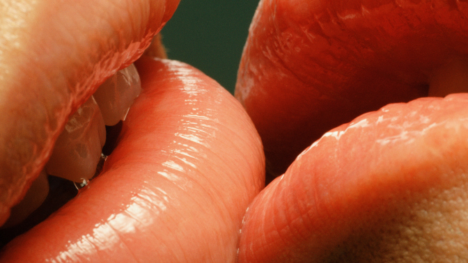 A close up of two people's lips touching. 