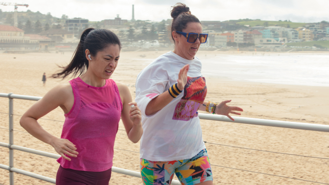 Two women jog along Bondi Beach.