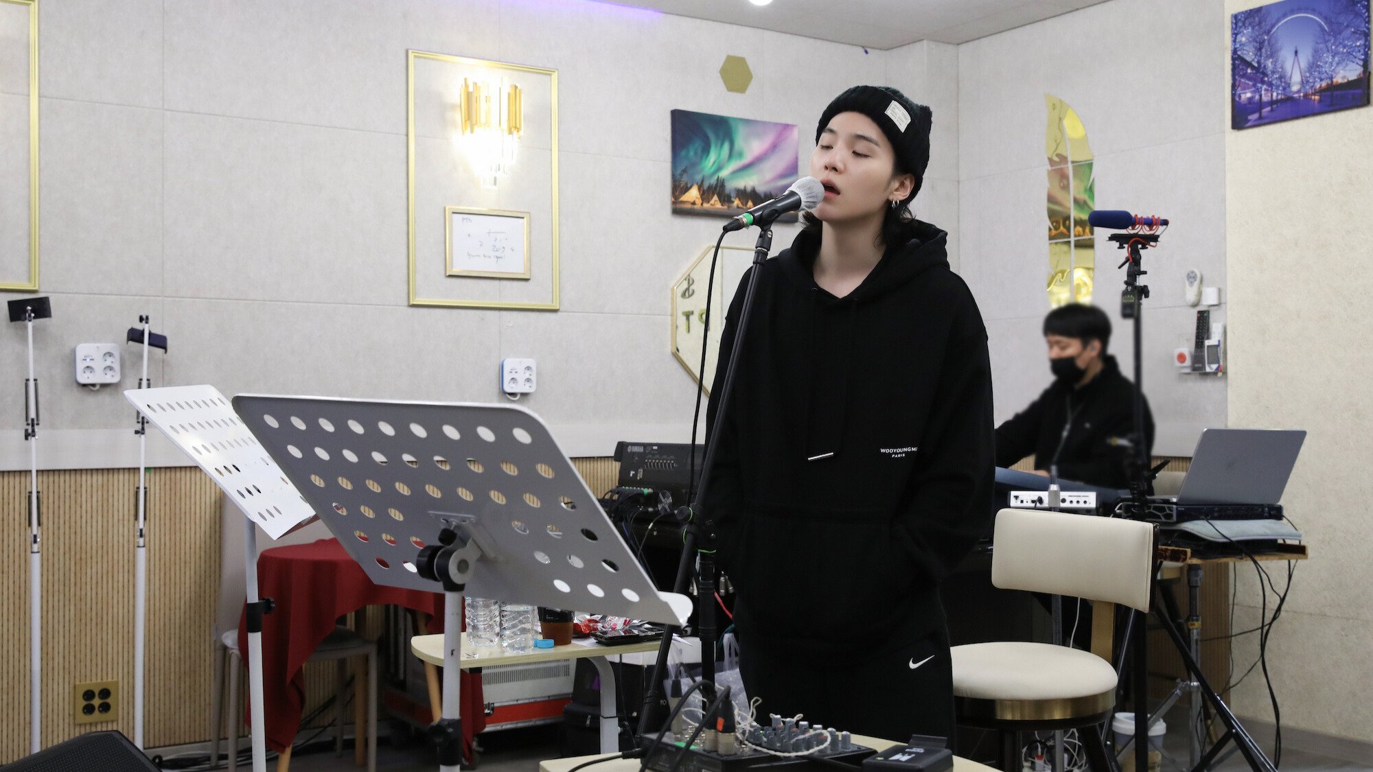 Suga from BTS records in a white studio room. 