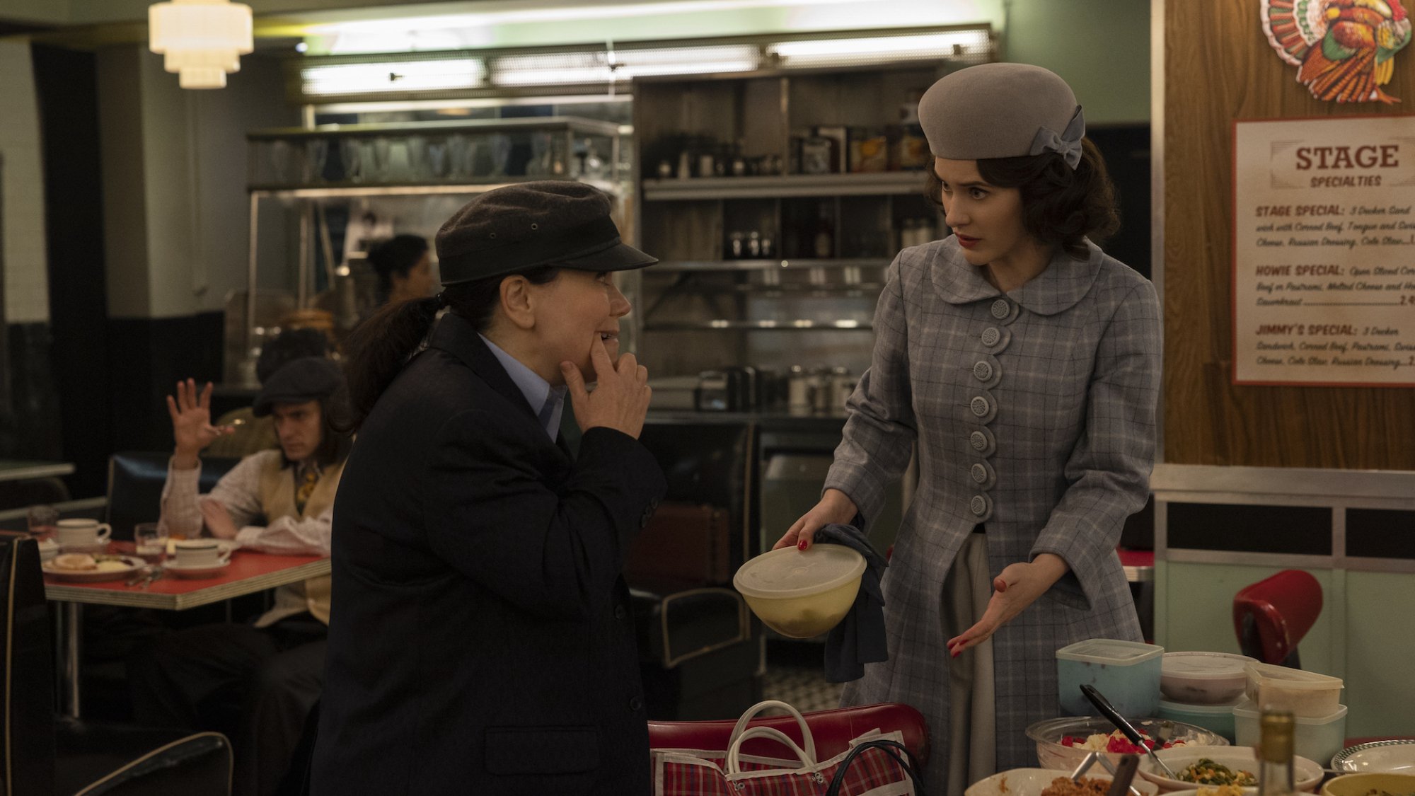 Two women stand in a diner conversing over tupperware in "The Marvelous Mrs Maisel"