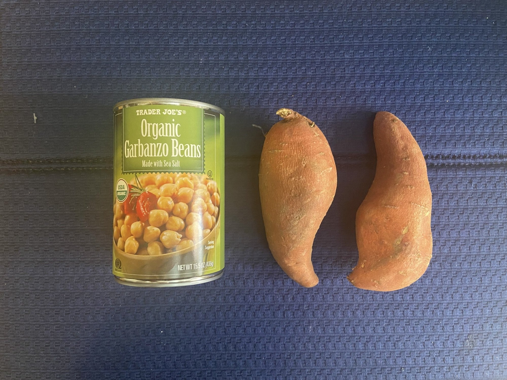 can of trader joes garbanzo beans next to two sweet potatoes 