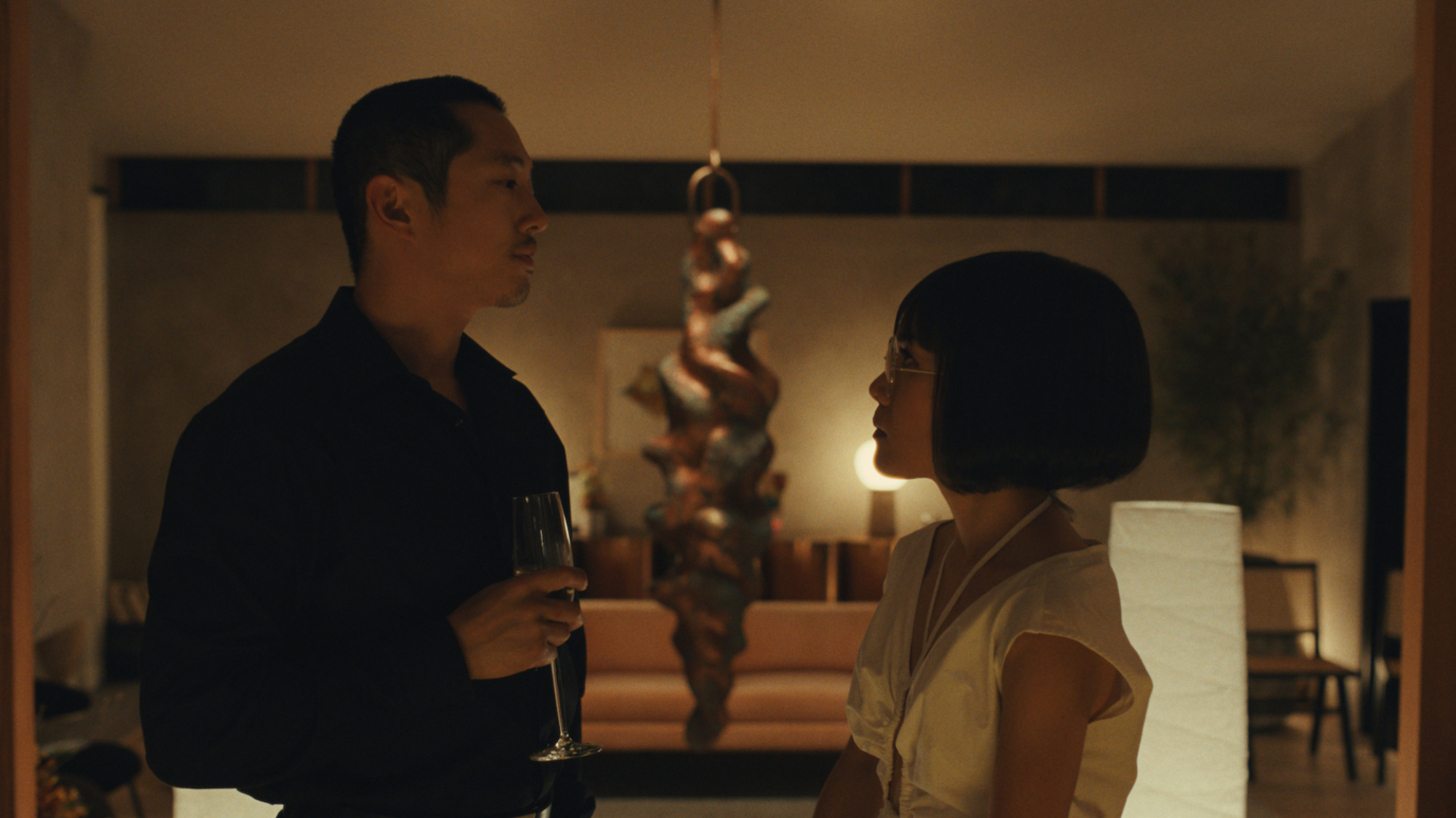 Actors Steven Yeun and Ali Wong face each other at a party in "Beef".