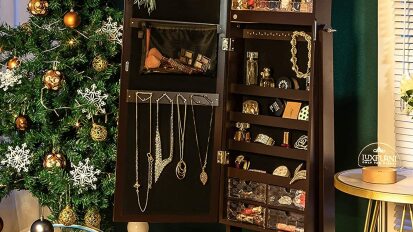 Brown cabinet open to show mirror and jewelry on hooks, next to christmas tree
