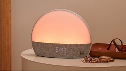 A sunrise alarm clock on a bedside table