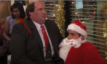 A man sitting on the lap of a man dressed as Santa Claus. An arrow points to a woman laughing in the background.