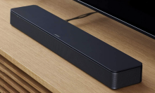 Black Bose soundbar over wood TV stand