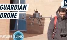 An autonomous drone following a man wearing a red backpack
