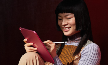 Woman using an iPad with a red cover and an Apple pencil (1st generation)
