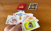 Manicured hand holding exploding kittens cards