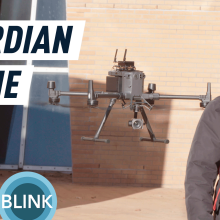 An autonomous drone following a man wearing a red backpack