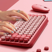 Hands with silver rings using pink Logitech keyboard and mouse