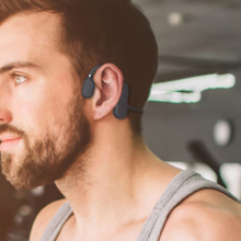 man wearing open ear headphones in gym