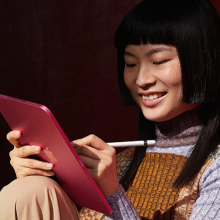 Woman using an iPad with a red cover and an Apple pencil (1st generation)