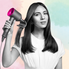 Woman using Dyson Supersonic hair dryer on pastel background