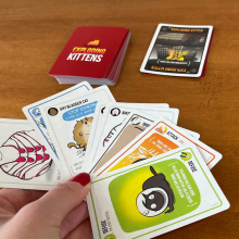 Manicured hand holding exploding kittens cards