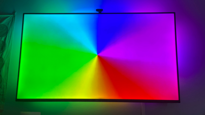 TV with rainbow wheel onscreen and matching colored lights behind the TV