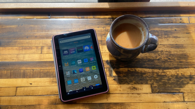 an amazon fire 7 tablet in a case sitting next to a cup of coffee on a wooden table