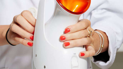 Hands holding white and orange facial steamer